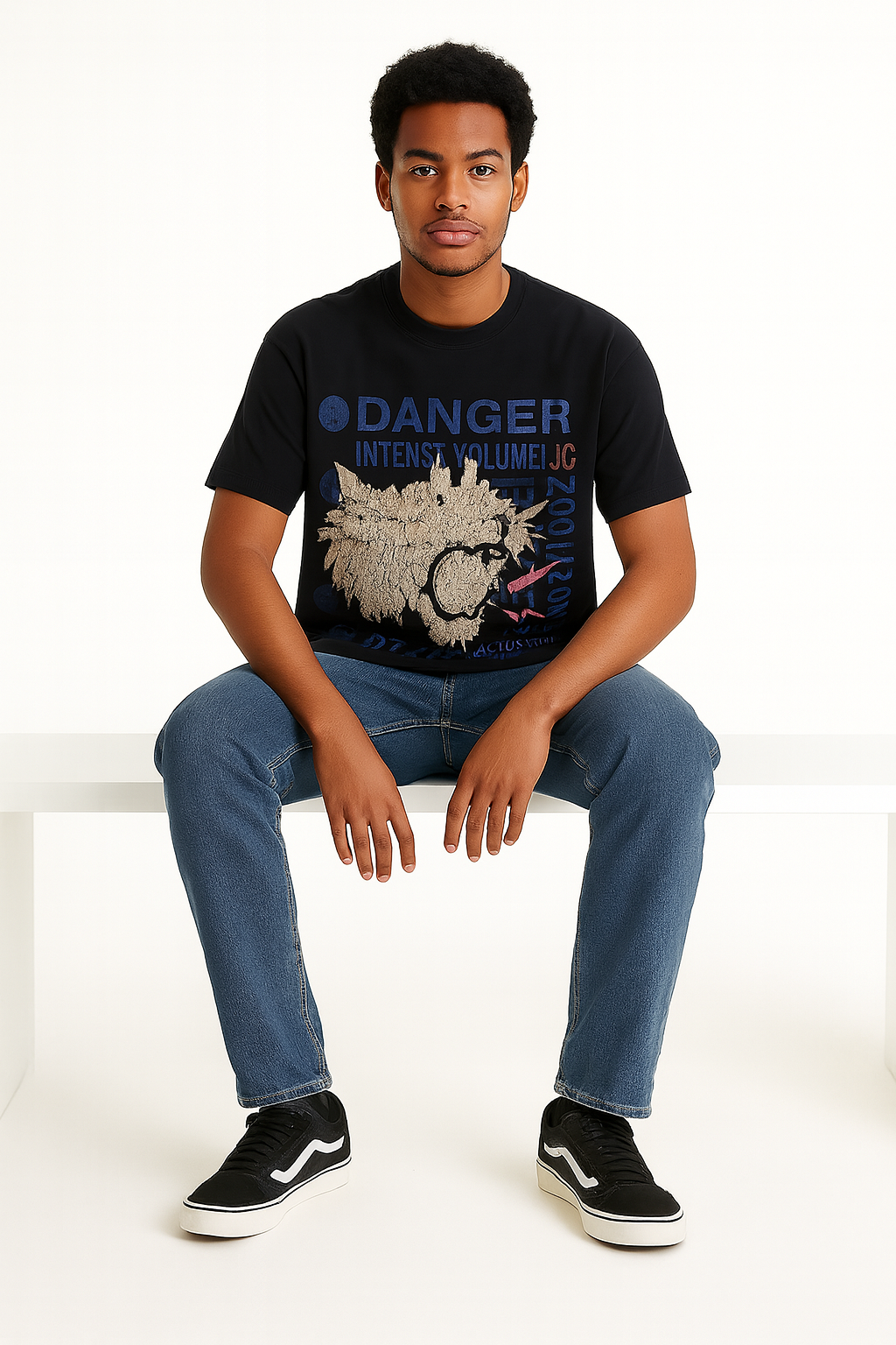 Person wearing a black t-shirt with graphic design and text, sitting on a white chair.